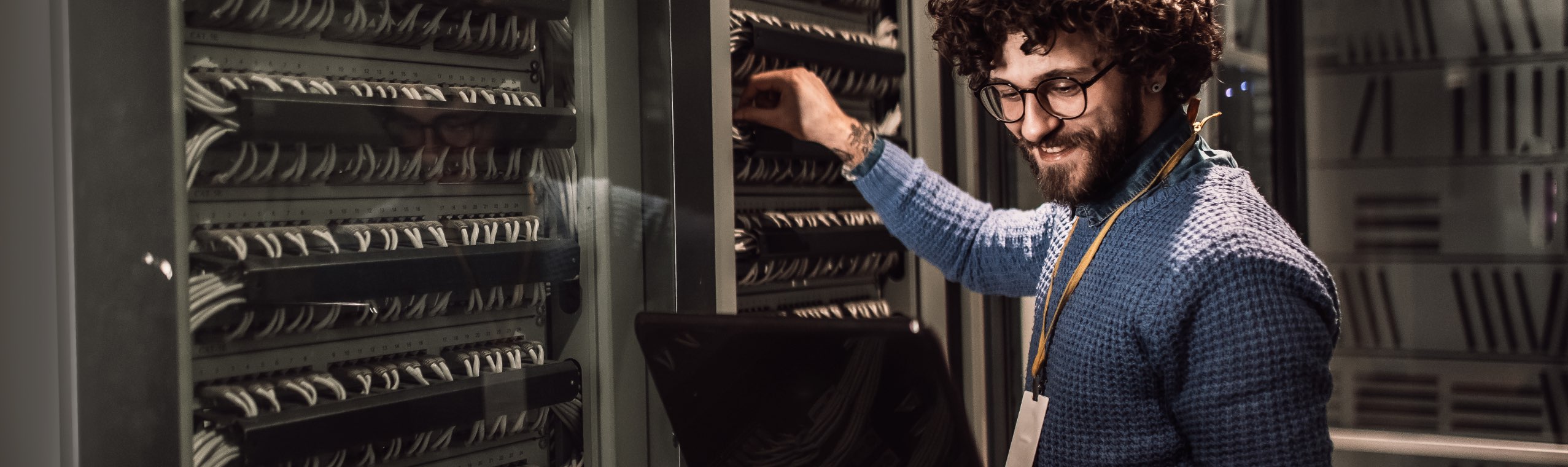 Business Man adjusting server rack while holding laptop